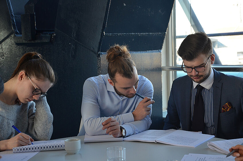 Three students at a table reading and working