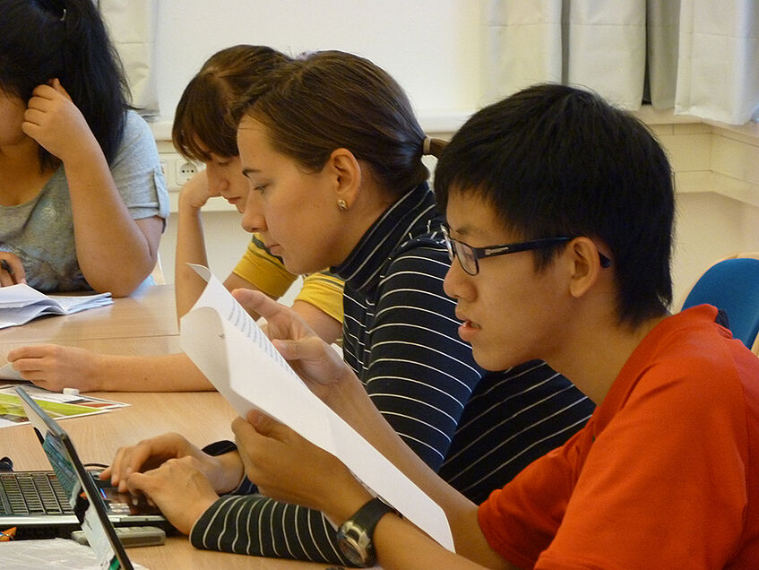 A row of four students sitting in class reading.