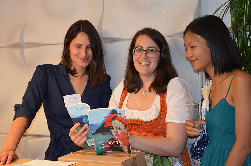 F.l.t.r.: Verena Bauer (Program Coordinator), Ana Kumin (Office Assistant), and an alumna with the anniversary publication.