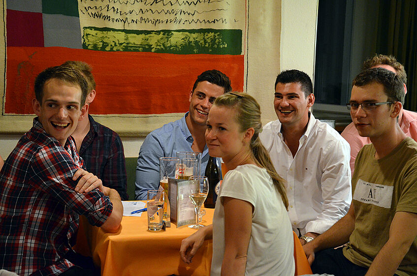 Students sitting around a table and looking towards a a point off the picture.